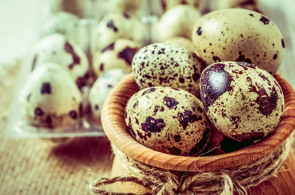 Raw quail eggs in a wooden bowl on burlap background — Stock Photo, Image