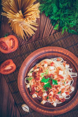 Tavuk soslu makarna, maydanozla süslenmiş domates..