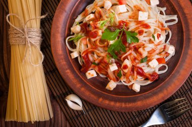 Tavuk soslu makarna, maydanozla süslenmiş domates..