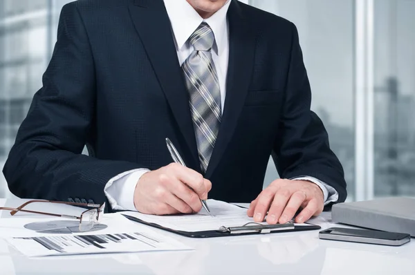 Joven hombre de negocios firmando un contrato en la oficina. El concepto de un negocio exitoso — Foto de Stock