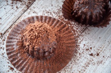 Çikolatalı kek, kahverengi yağlı kâğıt. Unwrapped. Arka planda kakao tozu