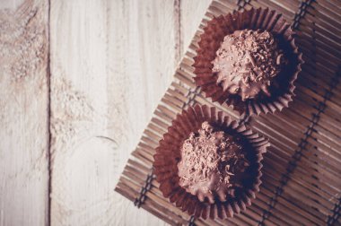 Çikolatalı kek, kahverengi yağlı kâğıt. Unwrapped. Arka planda kakao tozu