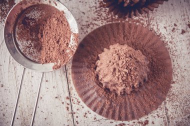 Çikolatalı kek, kahverengi yağlı kâğıt. Unwrapped. Arka planda kakao tozu