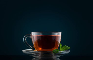 Çay bardağı nane ile karanlık bir arka plan üzerinde bırakır