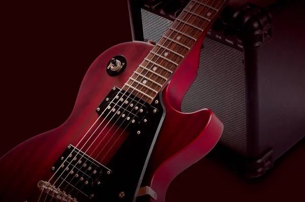 एक अंधेरे पृष्ठभूमि पर लाल इलेक्ट्रिक गिटार और क्लासिक एम्पलीफायर — स्टॉक फ़ोटो, इमेज