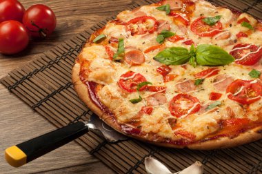 Sıcak pizza dilimi, erimiş peynirle ahşap bir masada.