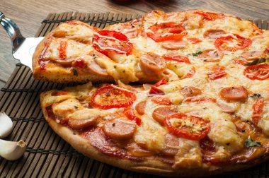 Sıcak pizza dilimi, erimiş peynirle ahşap bir masada.