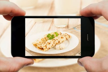 Gözleme fotoğraf smartphone tarafından çekici. Sürecinin closeup görünümü. Kırpma yolları için smartphone ve eller ve bu resim dosyası içerir.