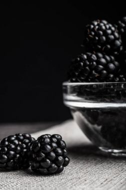 Siyah arka plan üzerine bir tabak içinde olgunlaşmış taze sulu böğürtlen