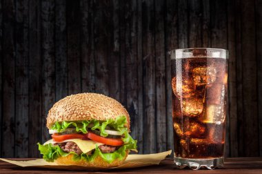 Lezzetli salata malzemelerin üzerine bir ızgara sığır patty boşaltmak bir rustik ahşap masada çizburger