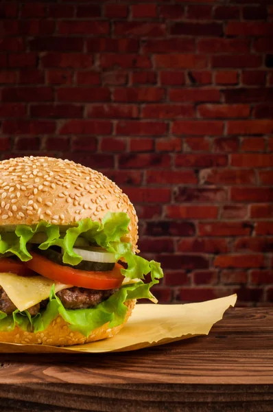 Lahodné cheeseburger s salát ingredience na grilované hovězí maso patty na rustikální dřevěný stůl s copyspace — Stock fotografie