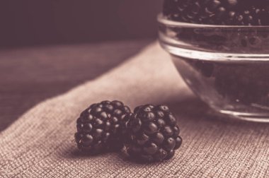 Siyah arka plan üzerine bir tabak içinde olgunlaşmış taze sulu böğürtlen