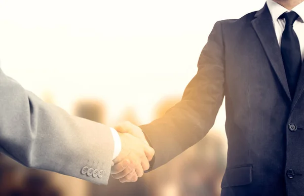 Handshake and business people concept. Two men shaking hands over sunny sity background. Partnership — Stock Photo, Image