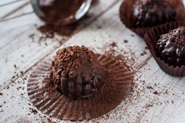 Çikolatalı kek, kahverengi yağlı kâğıt. Unwrapped. Arka planda kakao tozu