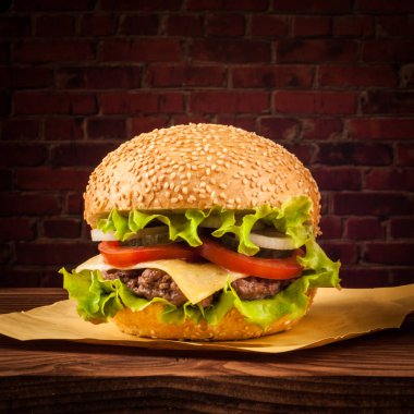 Lezzetli salata malzemelerin üzerine bir ızgara sığır patty boşaltmak bir rustik ahşap masada çizburger