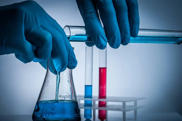 Vaso de precipitados de laboratorio en mano de analista en guante de plástico . — Foto de Stock