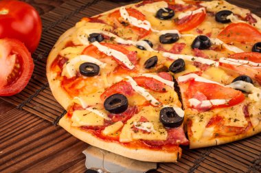 Sıcak pizza dilimi, erimiş peynirle ahşap bir masada.