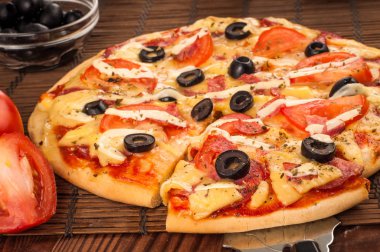 Sıcak pizza dilimi, erimiş peynirle ahşap bir masada.