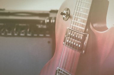 Kırmızı elektro gitar ve gri arka plan üzerinde klasik amplifikatör