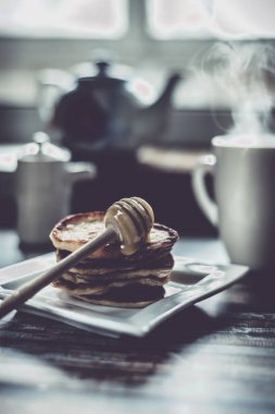 Lezzetli kahvaltı. Bal ve ahşap rustik arka plandaki tabloda çay ile ev yapımı gözleme. Vintage tarzı retro tonlu görüntü