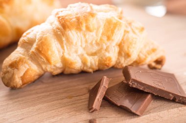 taze pişmiş kruvasanlar bir bardak süt ile ahşap kesme tahtası. Lezzetli kahvaltı