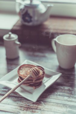 Lezzetli kahvaltı. Bal ve ahşap rustik arka plandaki tabloda çay ile ev yapımı gözleme. Vintage tarzı retro tonlu görüntü