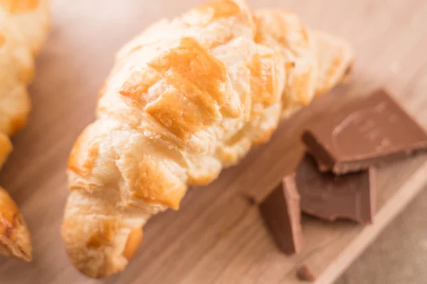 Frisch gebackene Croissants auf einem hölzernen Schneidebrett mit einem Glas Milch. Leckeres Frühstück — Stockfoto