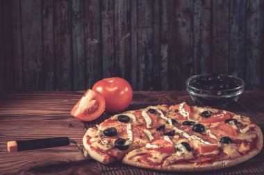 Sıcak pizza dilimi, erimiş peynirle ahşap bir masada.