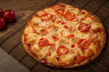 Sıcak pizza dilimi, erimiş peynirle ahşap bir masada.