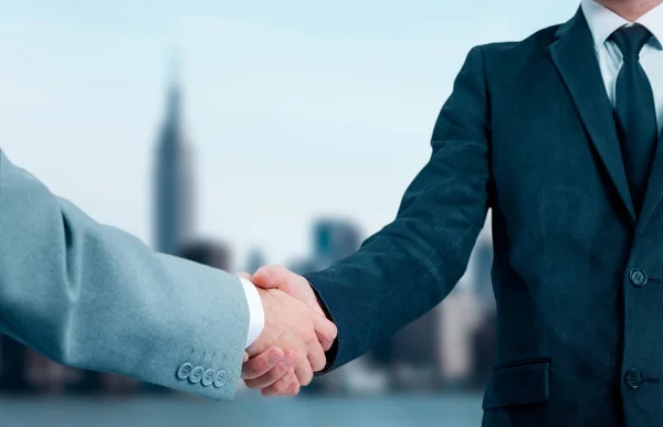 Business people shaking hands, finishing up a meeting. Business partners in the background of the city — Stock Photo, Image