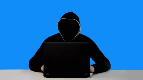 Hacker anónimo en capucha negra con un ordenador portátil — Vídeos de Stock