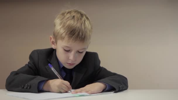 Серьезный мальчик пишет на своем блокноте — стоковое видео