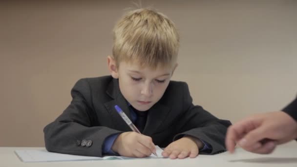 Учитель помогает мальчику писать — стоковое видео