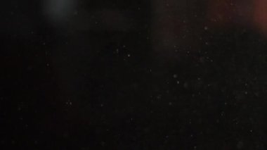 Toz parçacıklarının siyah arka plan üzerinde yavaş yavaş uçmak