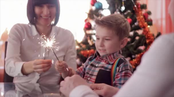 Feliz família e fogo de Bengala. Mãe segurando sparkler, então ela e o pai beijando criança enquanto ele olha para a luz. Movimento lento — Vídeo de Stock