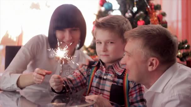 Familia feliz y fuego de Bengala. Madre sosteniendo chispa, entonces ella y su padre besan al niño mientras él mira la luz. Movimiento lento — Vídeo de stock