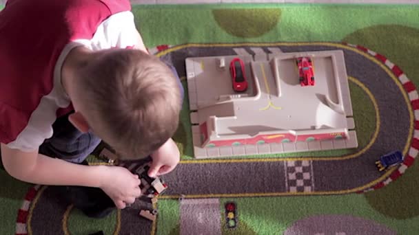 Blond chlapec hraje s auty na koberci — Stock video