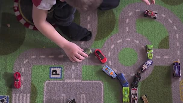 Little blonde boy plays with cars on carpet — Stock Video