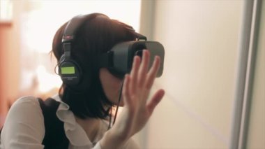 Genç esmer kadın oynarken oyun VR-kask akıllı telefonlar için kullanarak. Artırılmış gerçeklik aygıt derin sanal uzaya sağlar