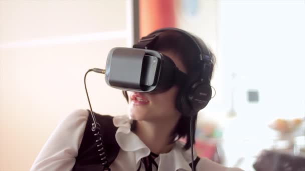 Молодая брюнетка играет в игры, используя VR-шлем для смартфонов. Устройство дополненной реальности позволяет глубоко проникнуть в виртуальное пространство — стоковое видео