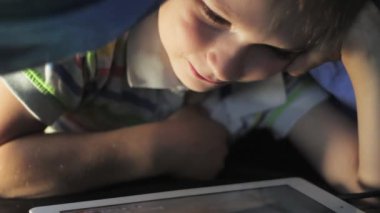 Oğlum battaniyenin altında yalan ve çizgi film izlerken dokunmatik yüzey