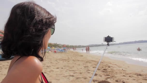 Meisje gebruik Selfie Stick te nemen foto's op zee strand — Stockvideo