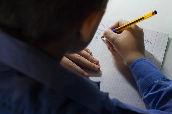 전통적인 흰색 메모장 종이에 손으로 영어 단어를 쓰는 연필 소년 손 클로즈업. — 스톡 사진