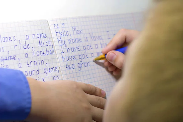 Detail ruky chlapce s tužkou psát anglická slova ručně na tradiční bílý Poznámkový blok papíru. — Stock fotografie