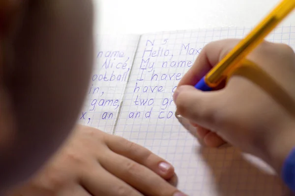 Primo piano di mano ragazzo con scrittura a matita parole inglesi a mano su carta taccuino bianco tradizionale . — Foto Stock