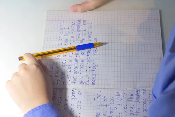 Close-up van de hand van de jongen met potlood schrijven van Engelse woorden met de hand op papier van de traditionele witte Kladblok. — Stockfoto