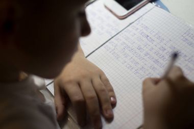 Yakın çekim çocuk el ile İngilizce kelime el ile geleneksel beyaz not defteri kağıda yazı kalem.