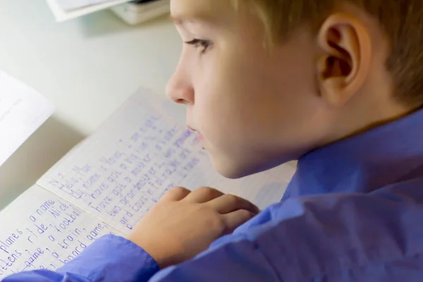 伝統的な白いメモ帳の紙に手で英単語を書く鉛筆と少年の手のクローズ アップ. — ストック写真
