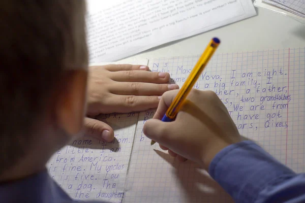 Γκρο πλαν του χεριού αγόρι με μολύβι γράφοντας λέξεις της αγγλικής γλώσσας με το χέρι σε παραδοσιακό άσπρο σημειωματάριο χαρτί. — Φωτογραφία Αρχείου