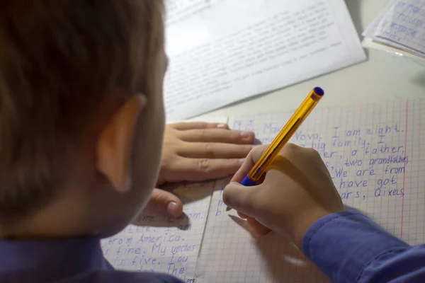 Close-up of boy hand with pencil writing english words by hand on traditional white notepad paper. — Stock Photo, Image